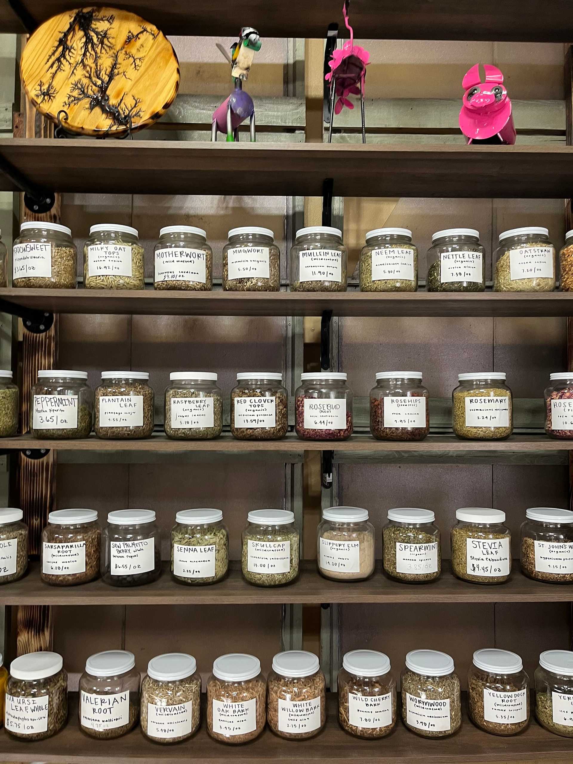 Shelves with various jars of herbs and spices, along with small colorful decorations placed above them.