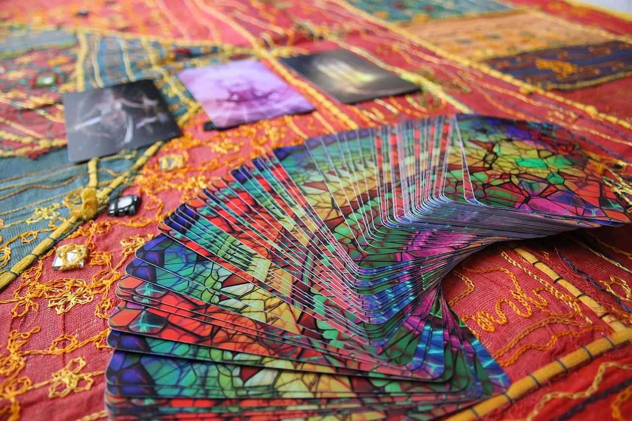 Colorful tarot cards spread on a vibrant tapestry with decorative patterns and stones.