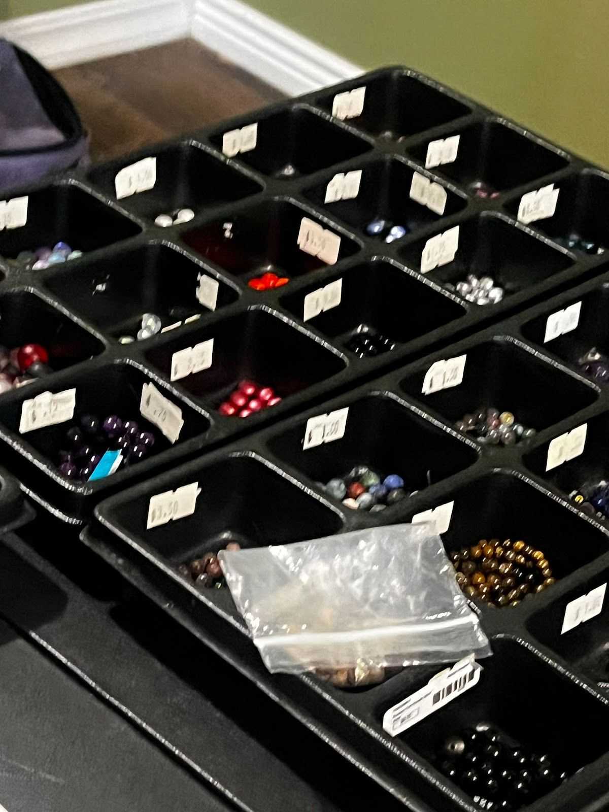 Assorted beads organized in labeled trays on a table.