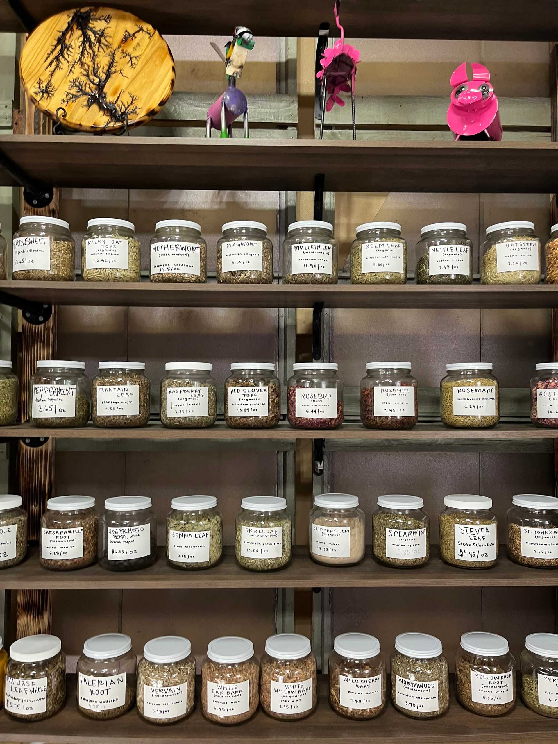 Shelves with various jars of herbs and spices, along with small colorful decorations placed above them.