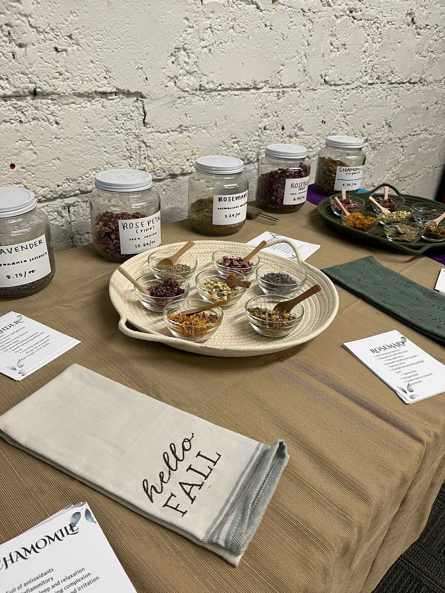 Table with jars of herbs and a 'Hello Fall' decorative sign.
